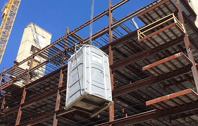 a porta potty being lifted up the side of a building